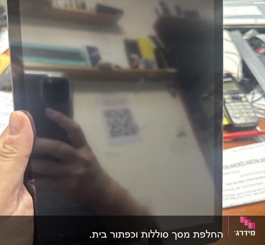 אדם מחזיק טאבלט עם כבל טעינה מחובר